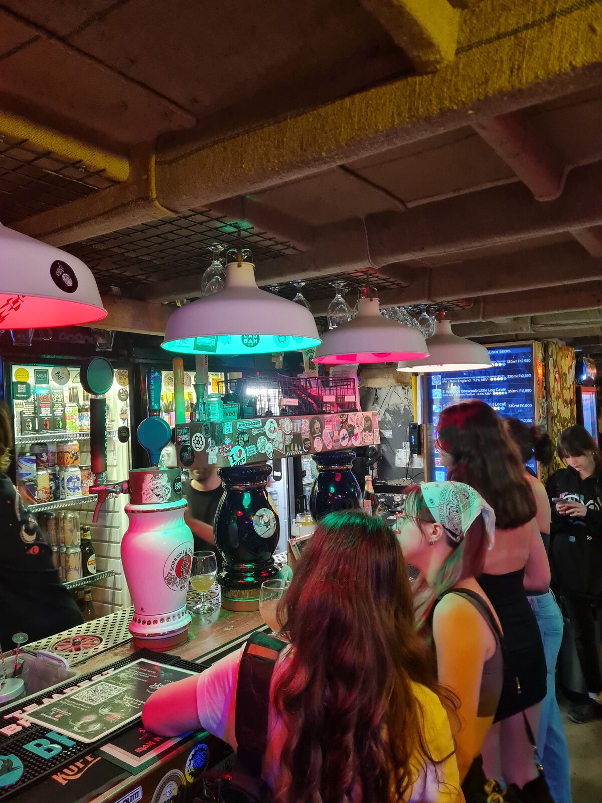 Interior of HOPS Beer Bar Budapest with walls covered in beer mats and graffiti stickers