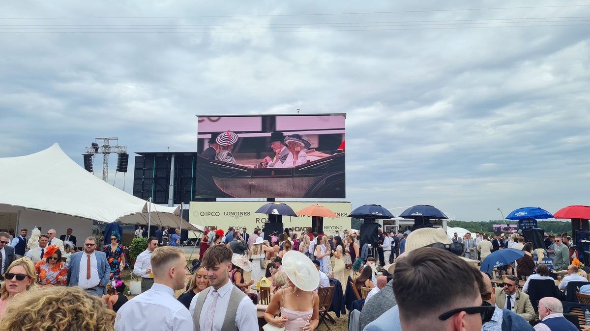 Village Enclosure crowd at Royal Ascot watching the Royal Procession on the big screen
