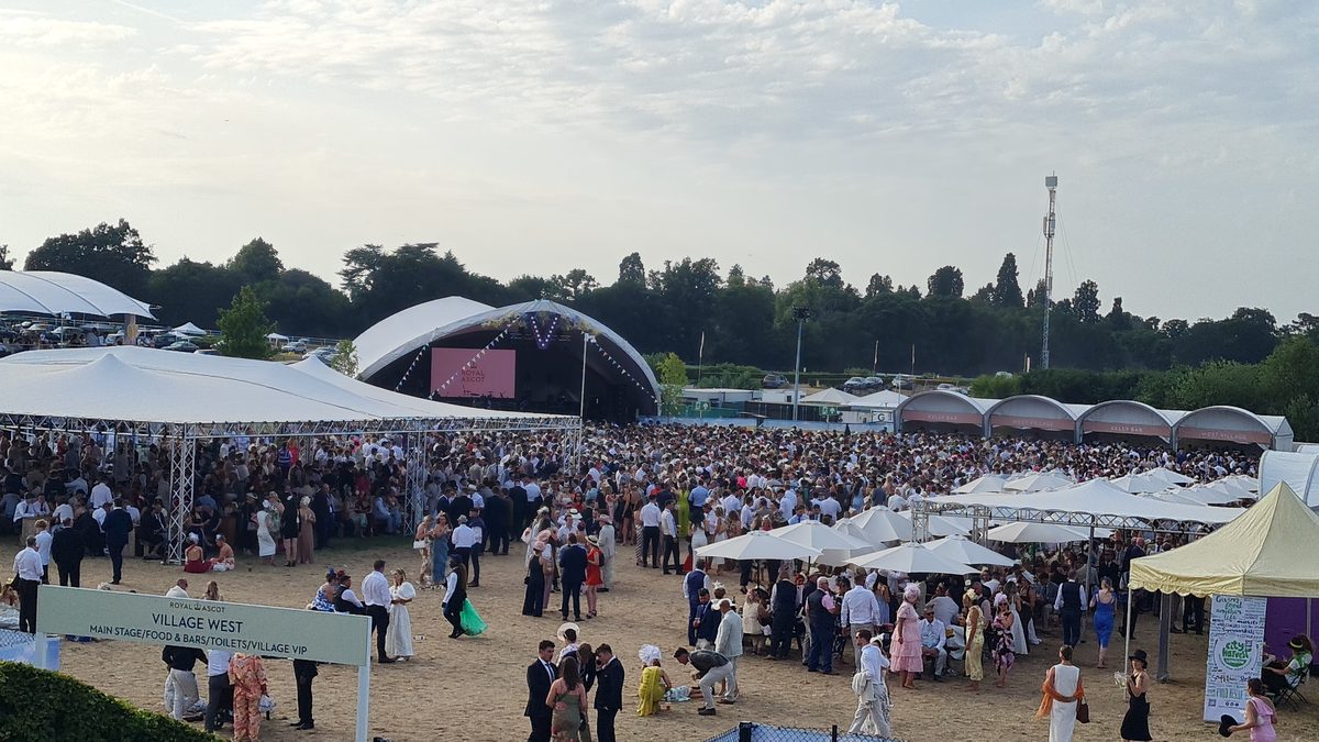 Royal Ascot Village Enclosure overview — Village West area showing the main stage, food and bar tents and thousands of racegoers