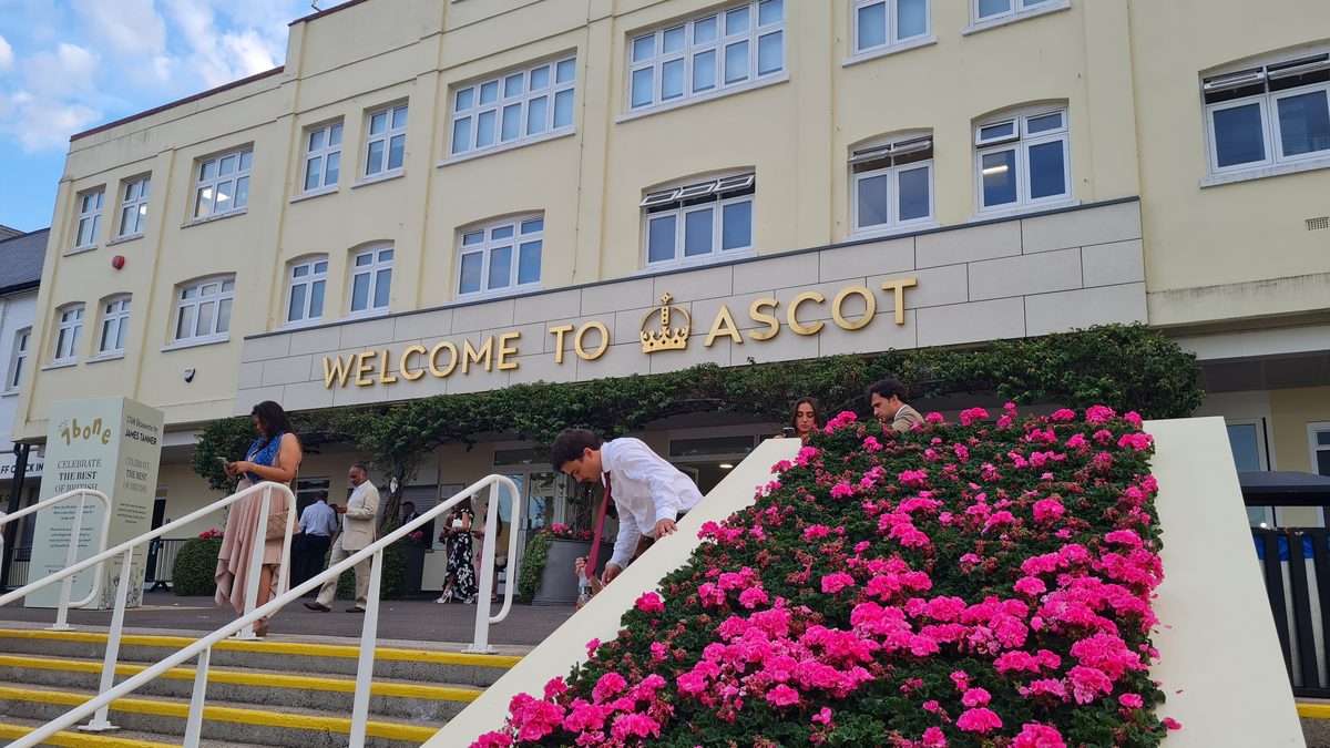 Welcome to Ascot sign with pink geranium flower display at the entrance building