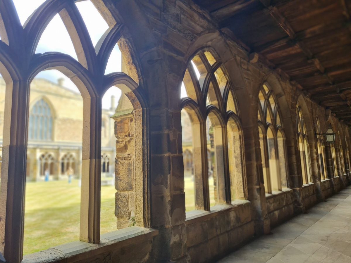 Arched cloister walkway at Durham Cathedral looking out onto the grass garth