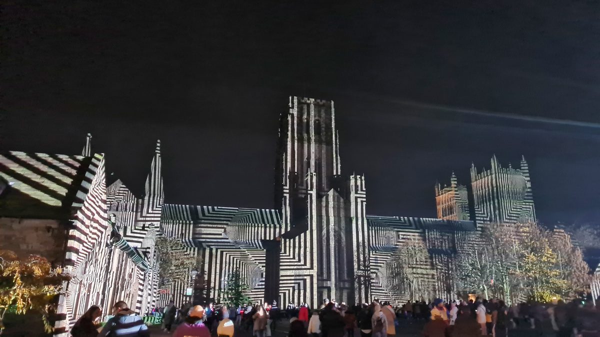 Coloured light projections on the west front of Durham Cathedral at night during Lumiere