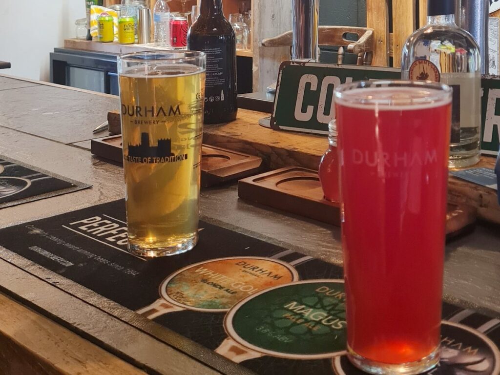 A pale ale and a red blackcurrant sour in Durham Brewery glasses on the bar