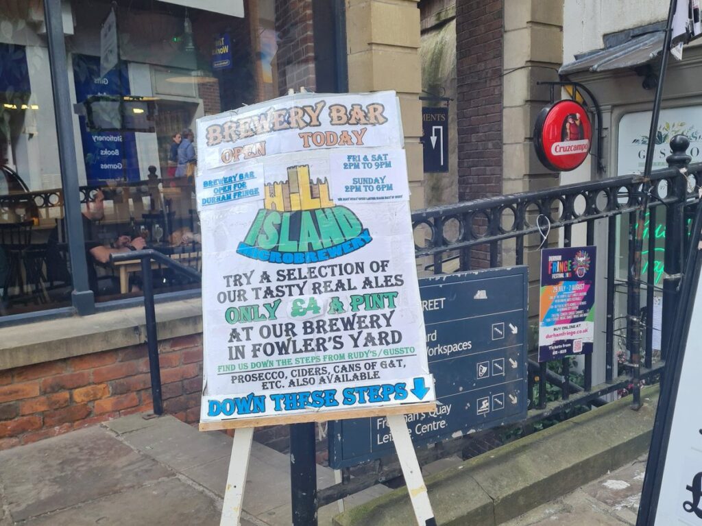 Hand-lettered A-board advertising the Hill Island brewery bar down the steps in Fowler’s Yard, Durham