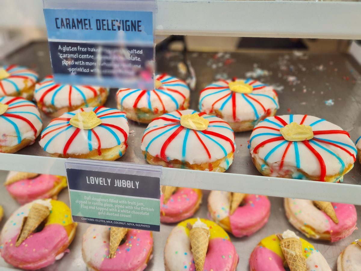 Coronation doughnuts in a Windsor bakery window, iced with British flags and gold crowns