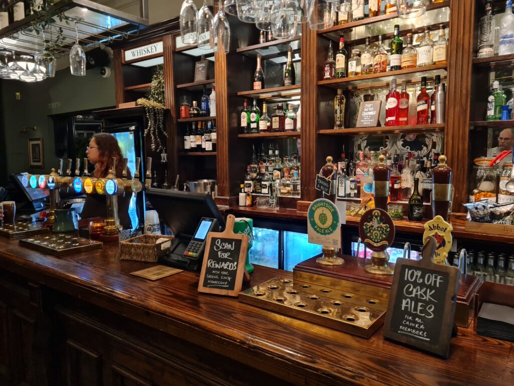 The bar at the Rutland Arms, Hammersmith, with hand pulls, a whisky shelf and a cask ale blackboard