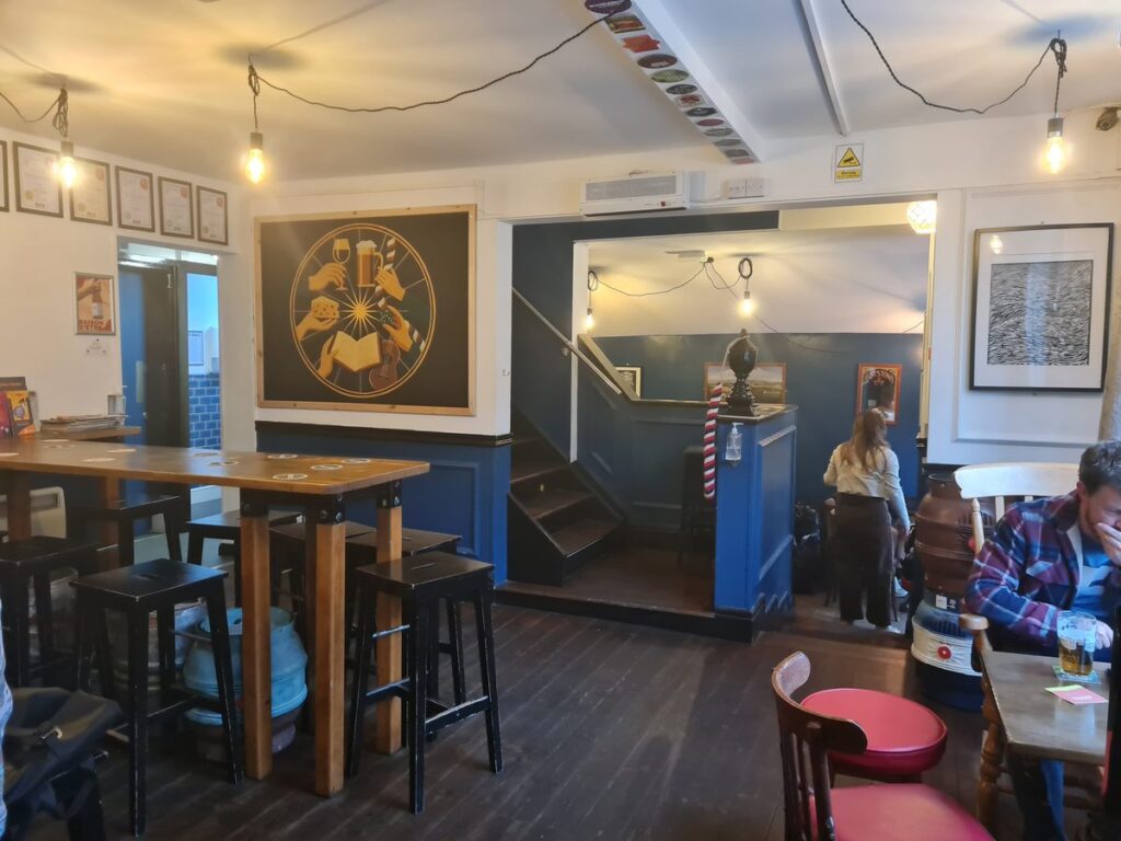 The blue-walled interior of The Station House, Durham, with bench tables and steps down to the back room