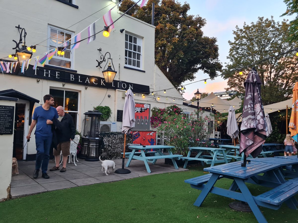 The Black Lion pub sign and beer garden with picnic benches, Hammersmith, London