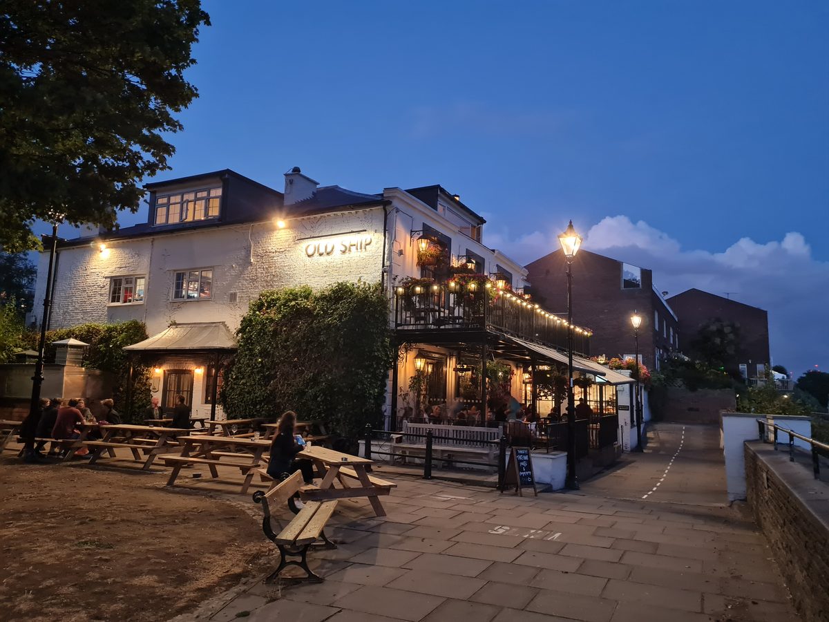 Riverside pubs lit up at dusk on the Hammersmith Thames path, London