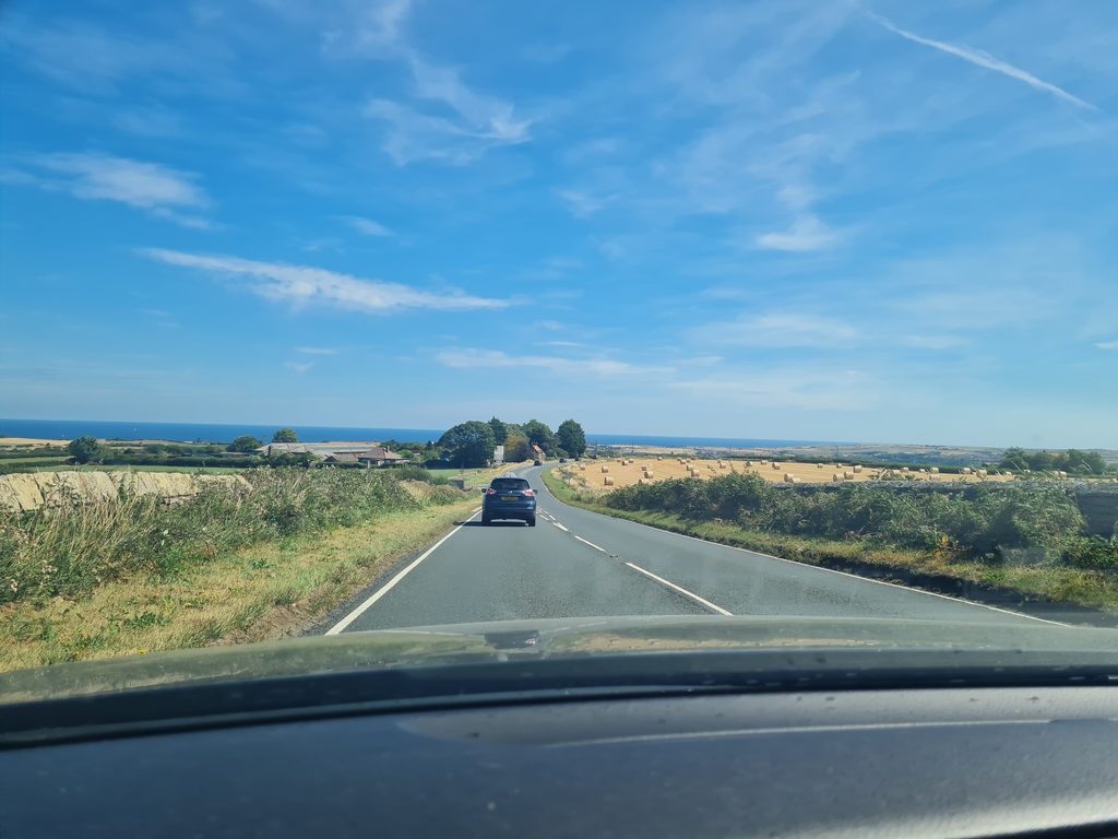 The moor road dropping down towards Whitby and the sea, seen through the car windscreen