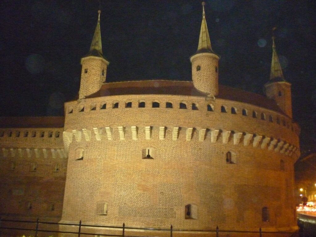 The round brick Barbican with its turrets, lit up at night, Kraków