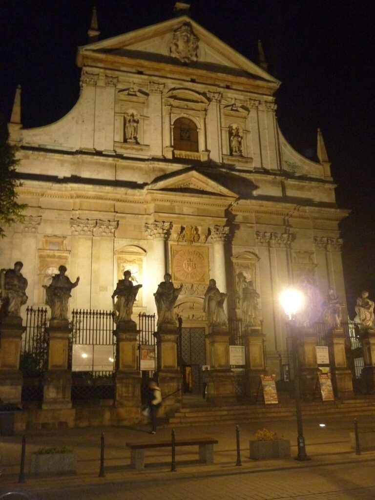 The Baroque church of Saints Peter and Paul on Grodzka Street at night, with statues of the apostles in front, Kraków