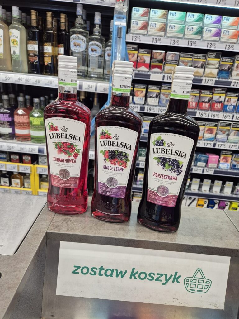 Three bottles of Lubelska fruit liqueur, cranberry, forest fruit and blackcurrant, on a shop counter in Kraków