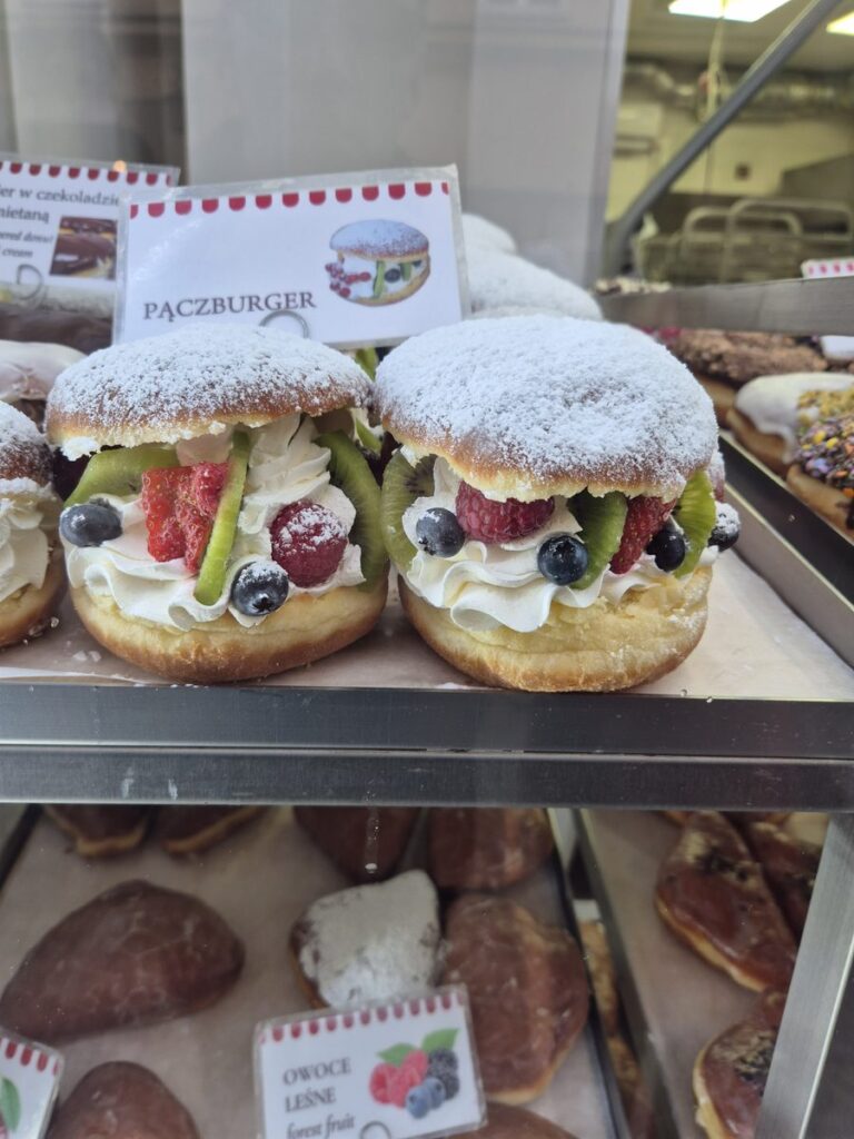 Doughnut 'burgers' filled with cream and fresh fruit, and wild berry hand pies, in a bakery window in Kraków's Old Town