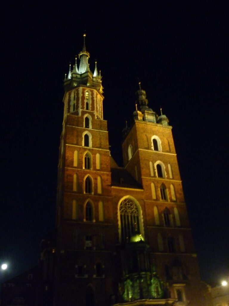 The two unequal brick towers of St Mary's Basilica lit up at night, Kraków