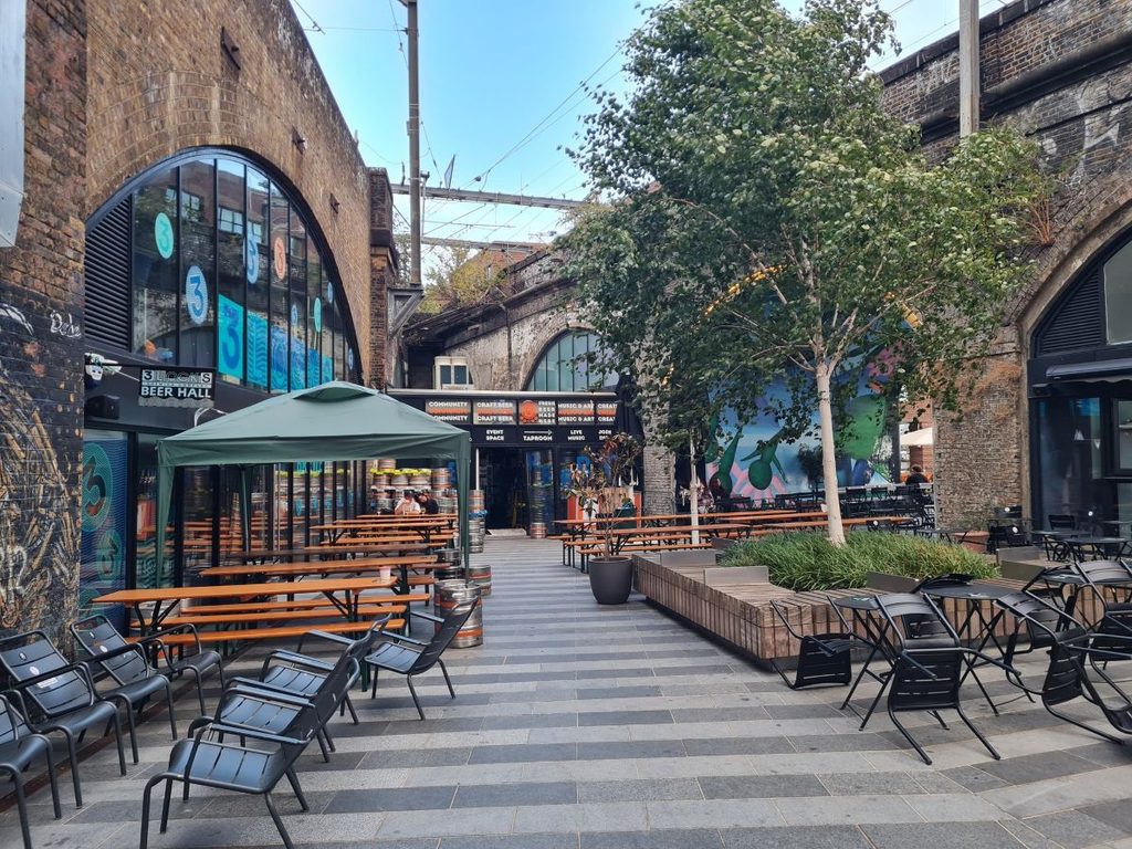 Outdoor tables outside 3 Locks Brewing Co under the railway arch at Hawley Wharf, Camden, London