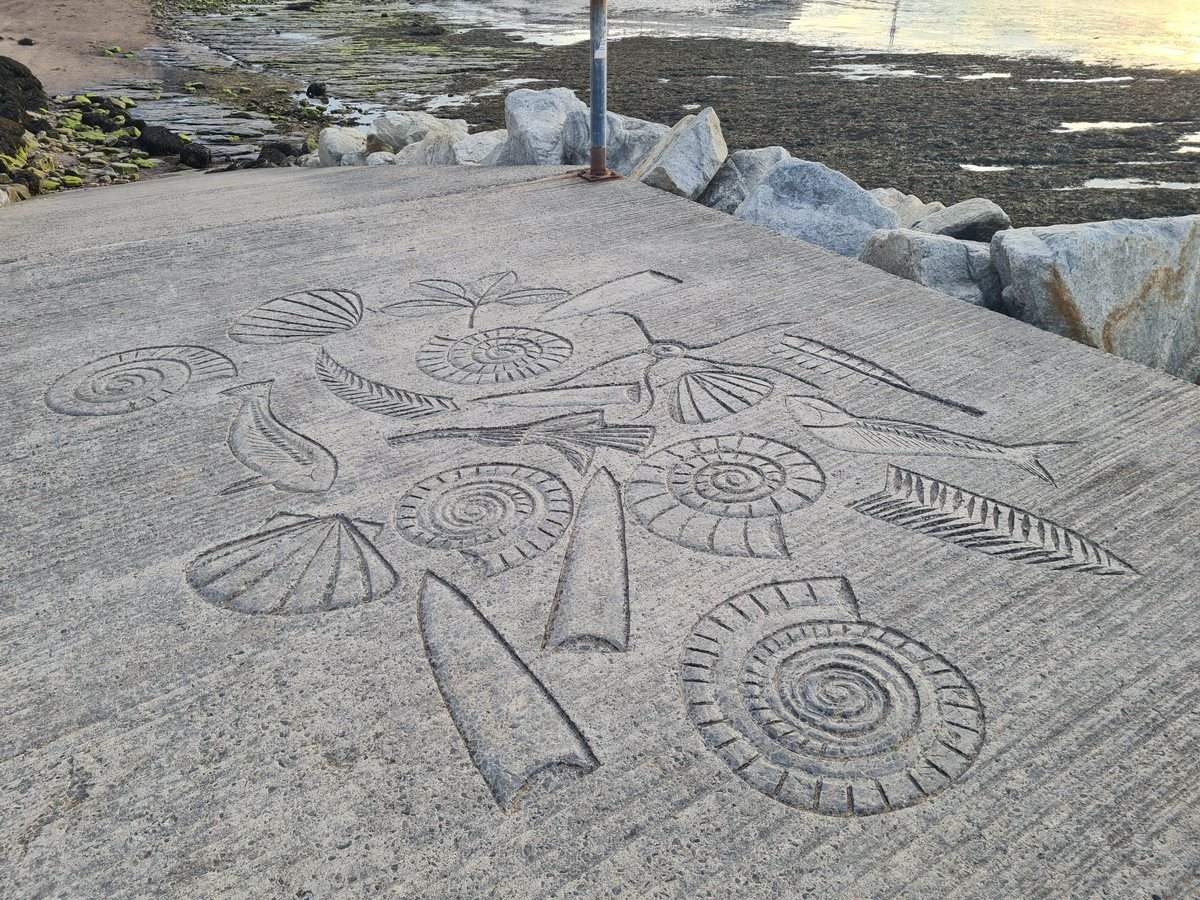 Ammonites and fossils carved into the stone path beside Whitby beach