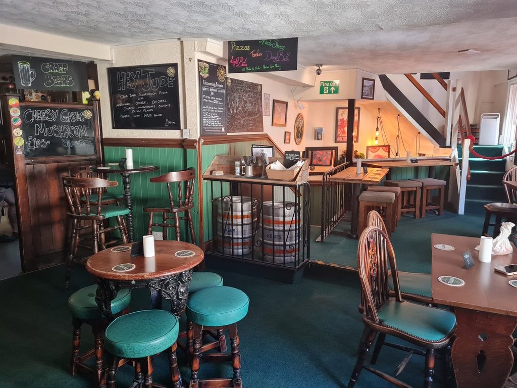 The plain green-panelled room at The Esk Vaults in Whitby, with casks, stools and chalkboards on the wall