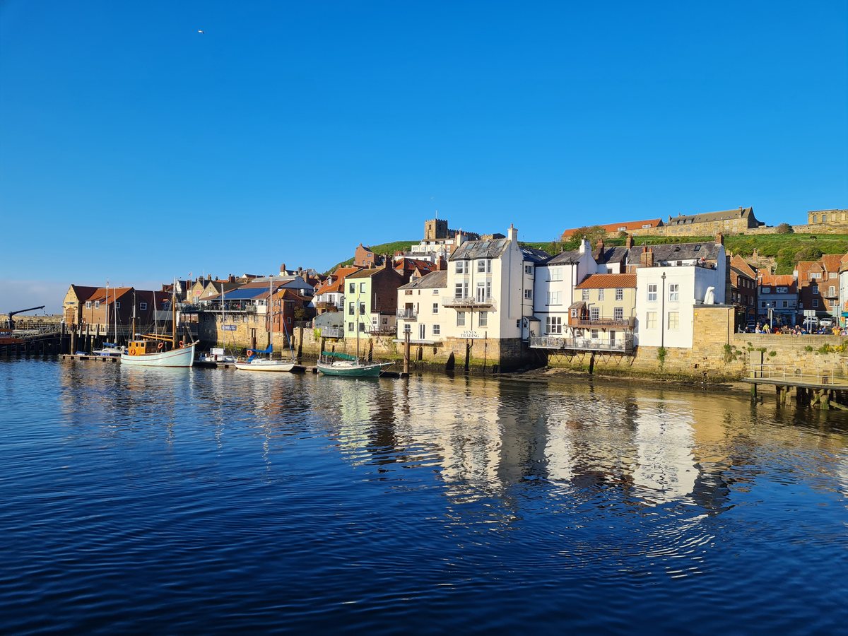 Whitby harbour and the East Cliff reflected in still water in the evening
