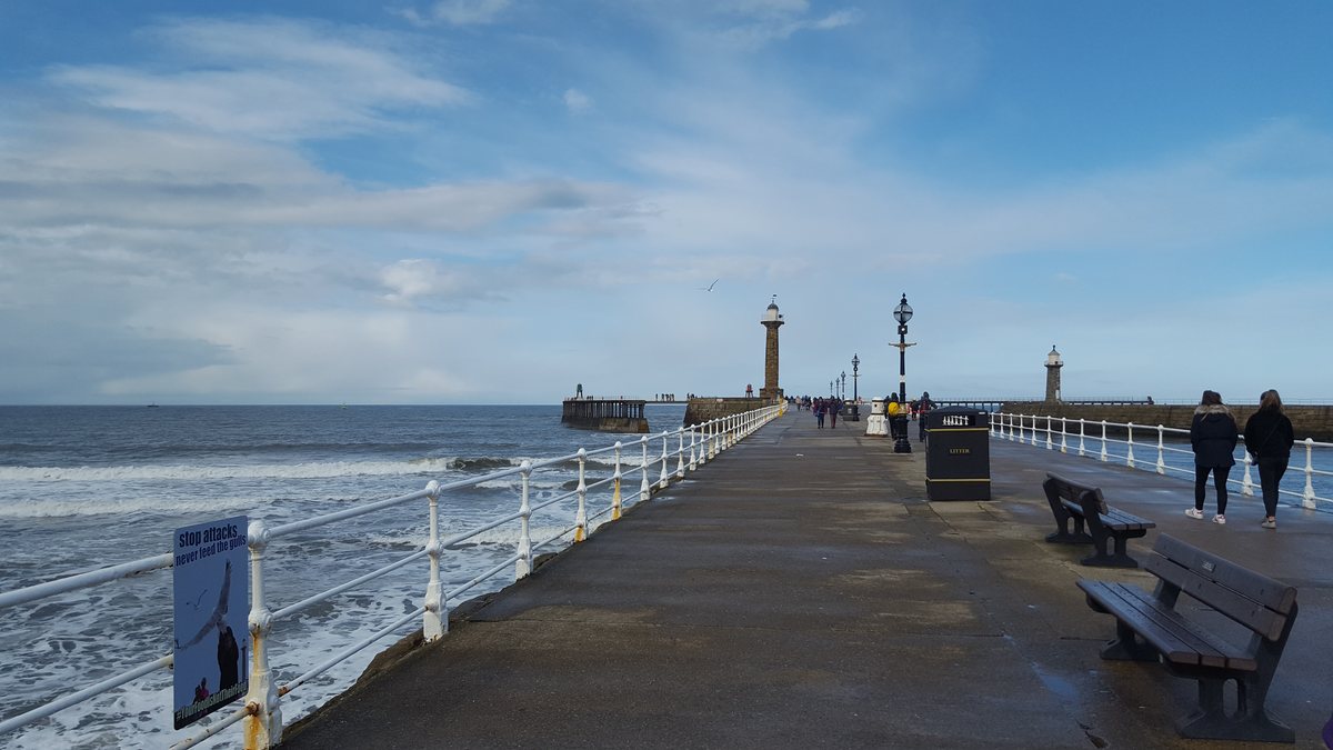 The walkway along Whitby's West Pier with a rough sea beyond the railing